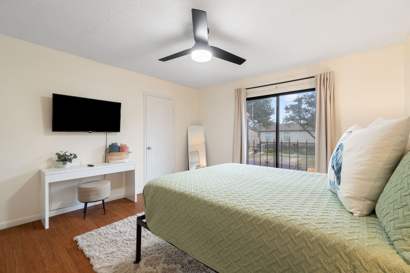 Guest bedroom with queen bed TV and balcony access