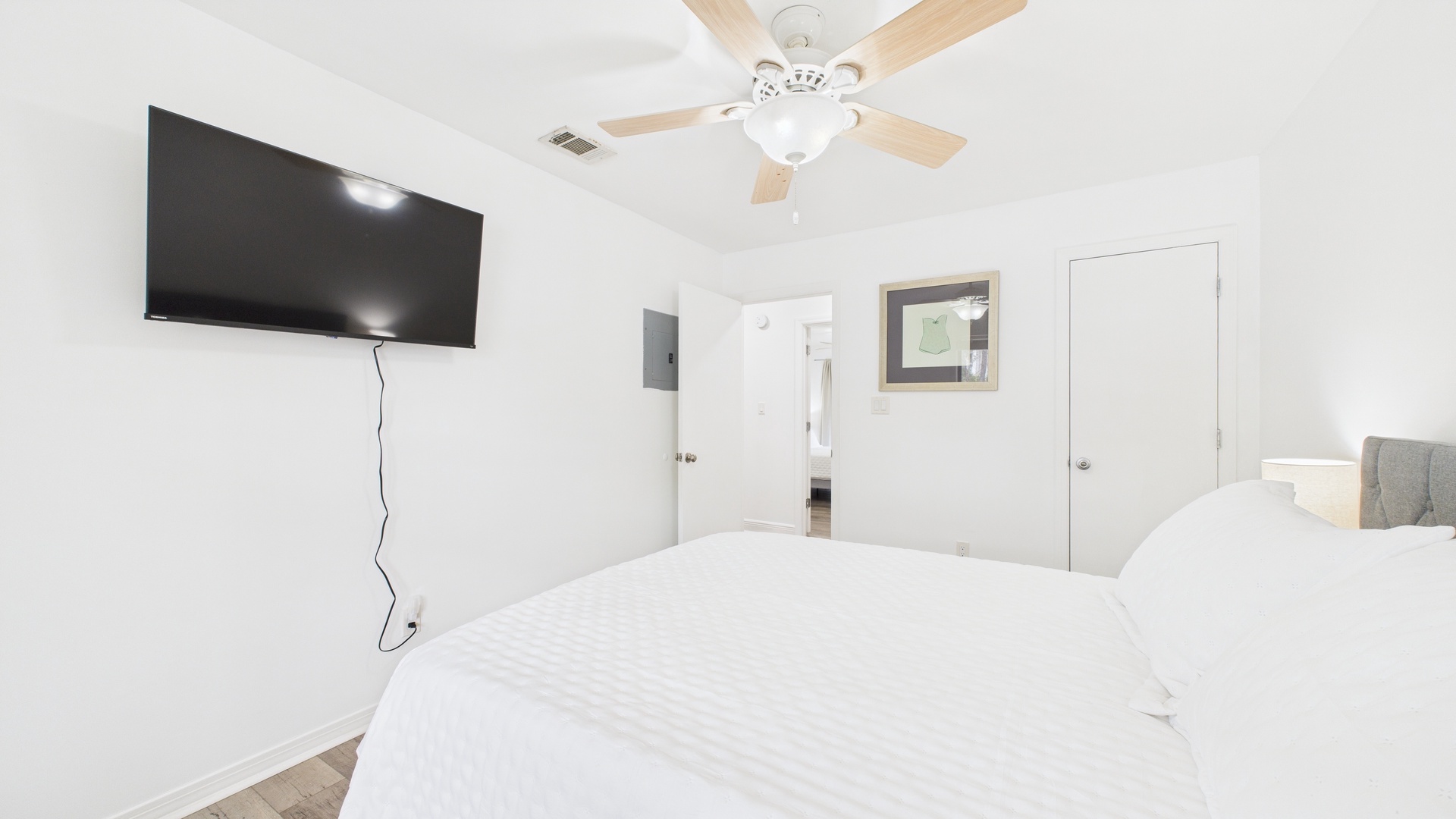 Guest bedroom with queen bed TV and balcony access