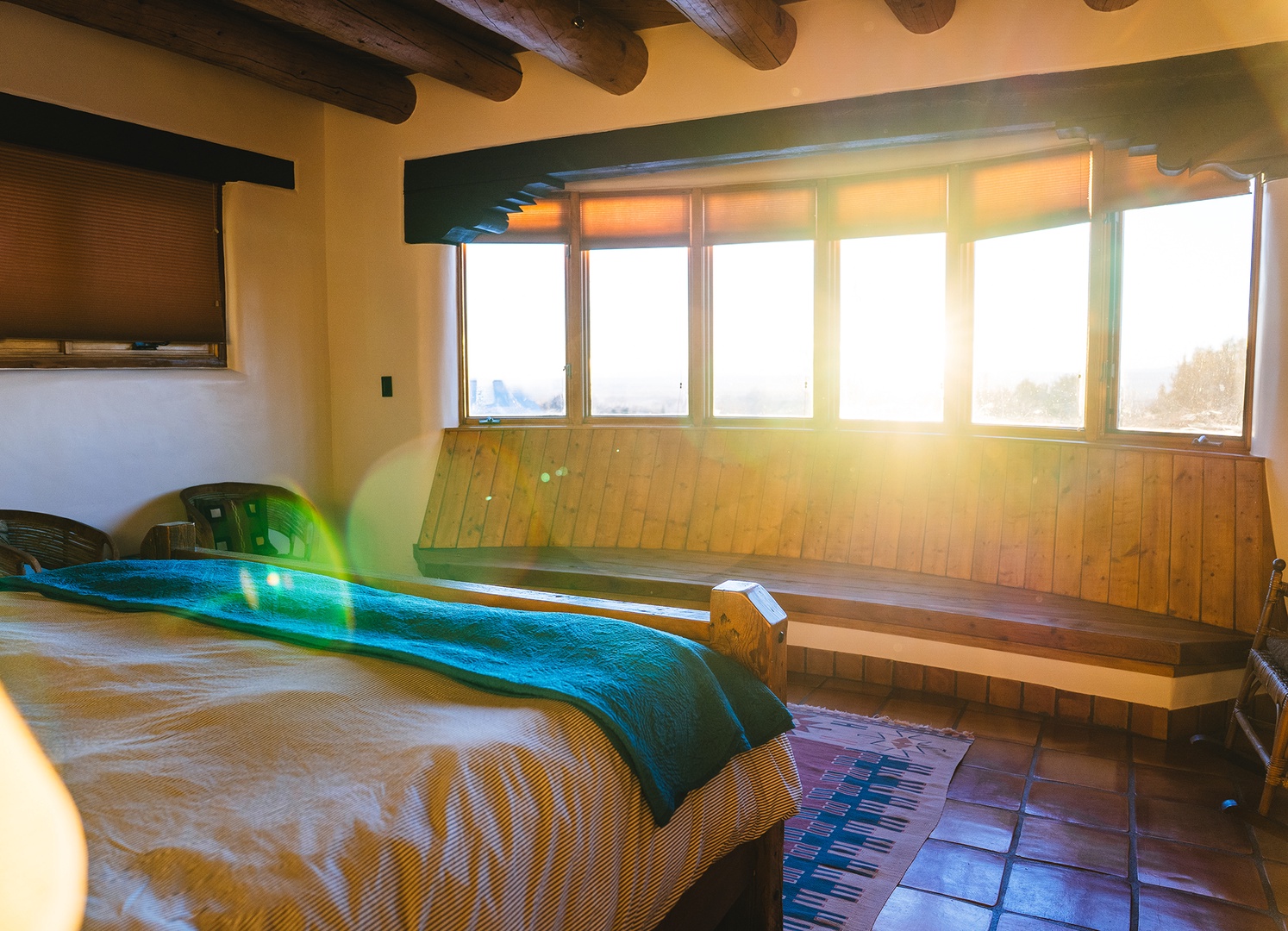 Wake up to golden sunlight streaming through expansive windows in your cozy bedroom, where rustic beams meet modern comfort.