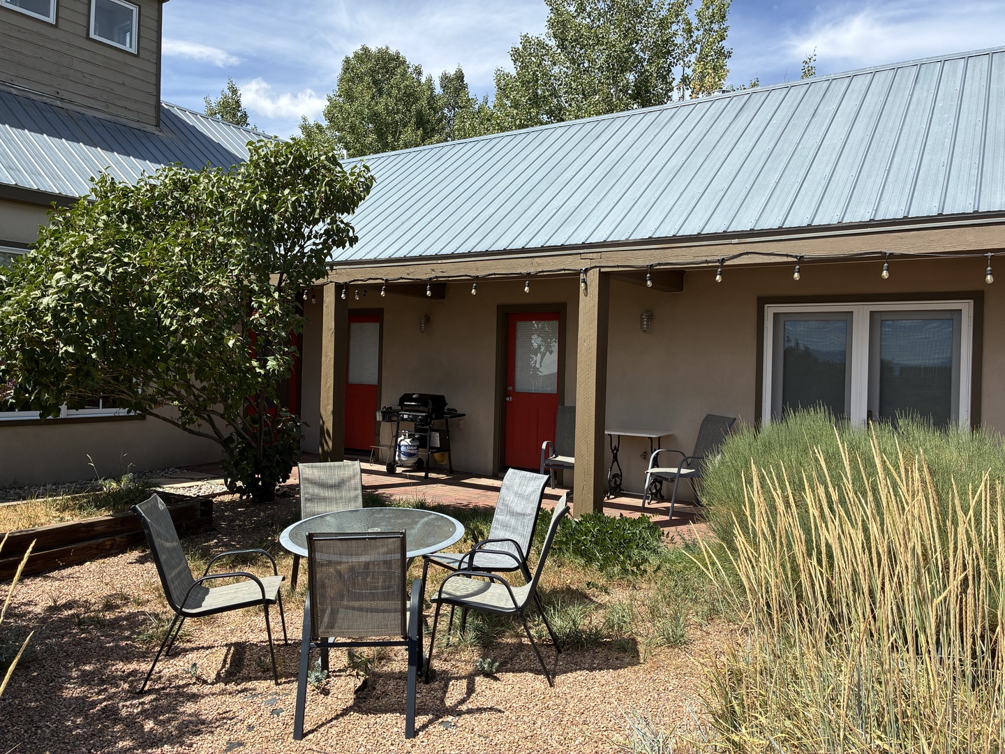 Inviting outdoor retreat featuring a covered patio with string lights, comfortable seating, and a BBQ grill—perfect for your morning coffee or evening gatherings under the open sky.