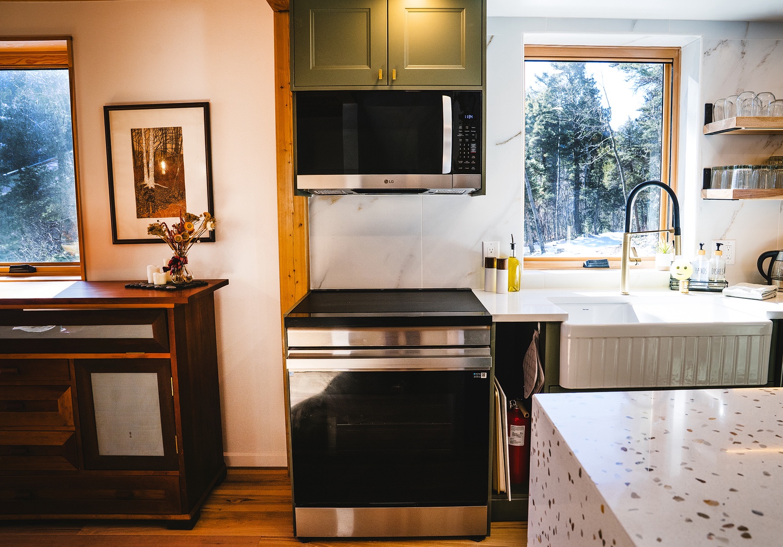 A fully equipped kitchen features modern appliances and forest views