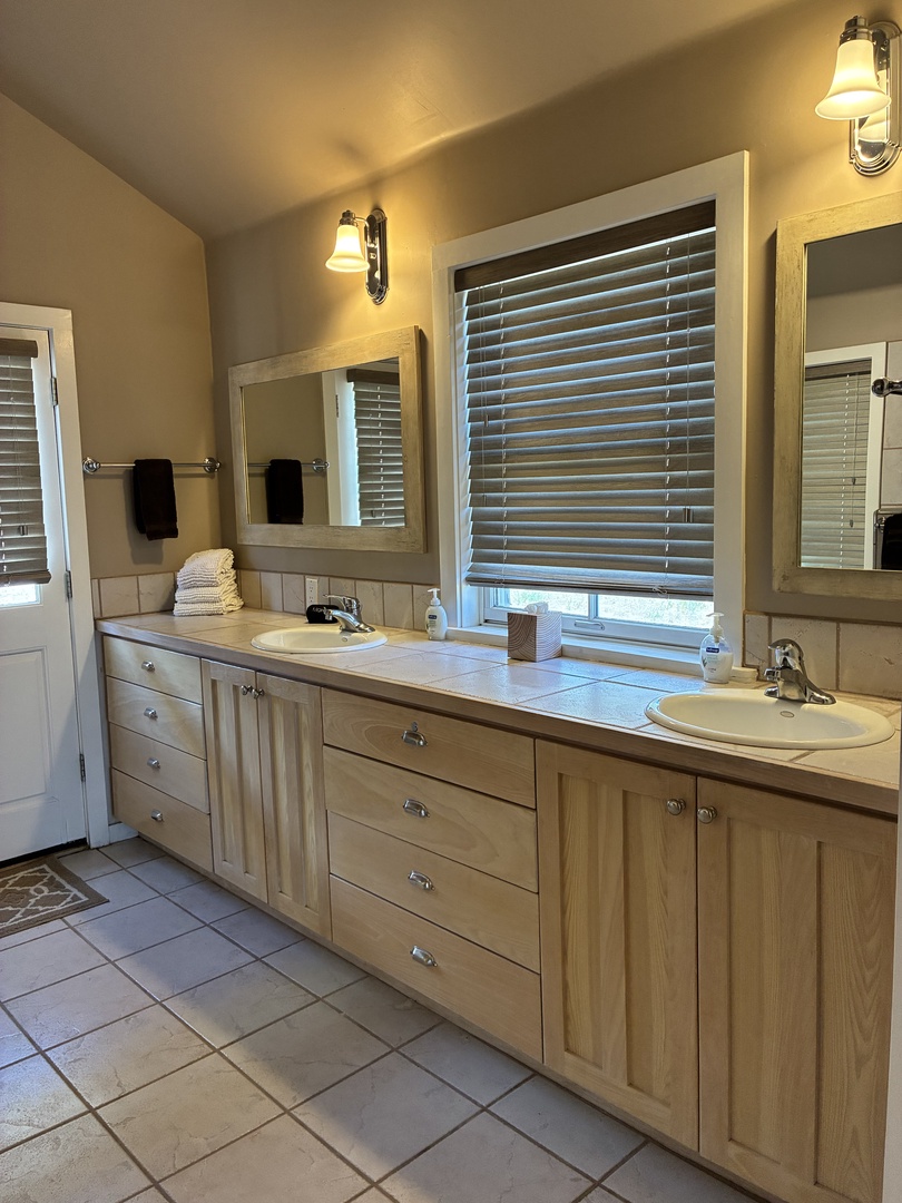 Fresh towels await you in this bright, spacious bathroom with a double vanity and gentle natural light—the perfect start to your mornings here.