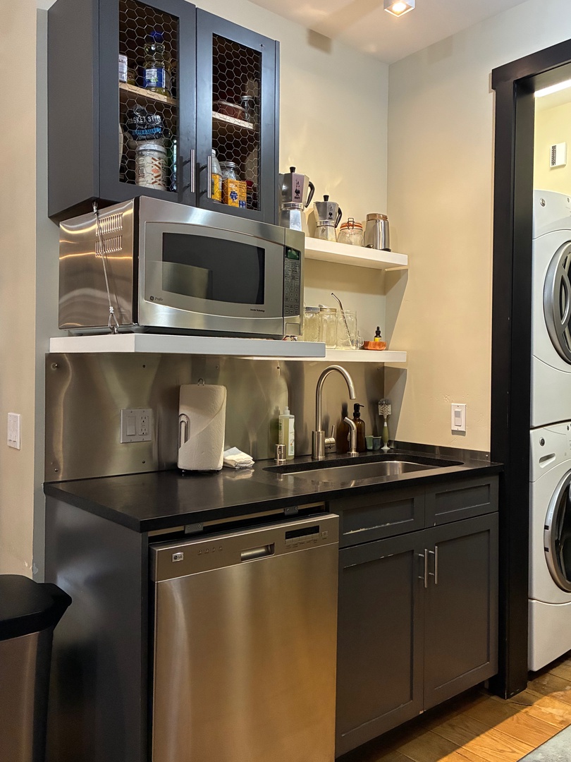 Your compact kitchenette has everything you need: a microwave, dishwasher, sink, and coffee essentials at your fingertips. Just beyond, in-unit laundry makes life simple and convenient.