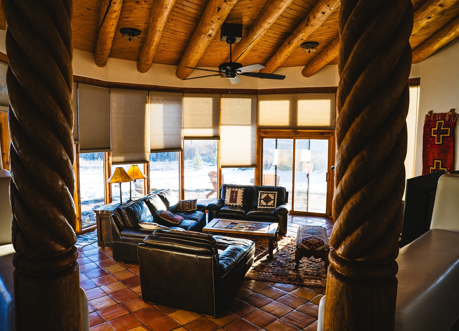 Sink into handcrafted leather seating beneath vaulted wood beam ceilings in your rustic-elegant living space, where mountain views frame perfect moments of relaxation.