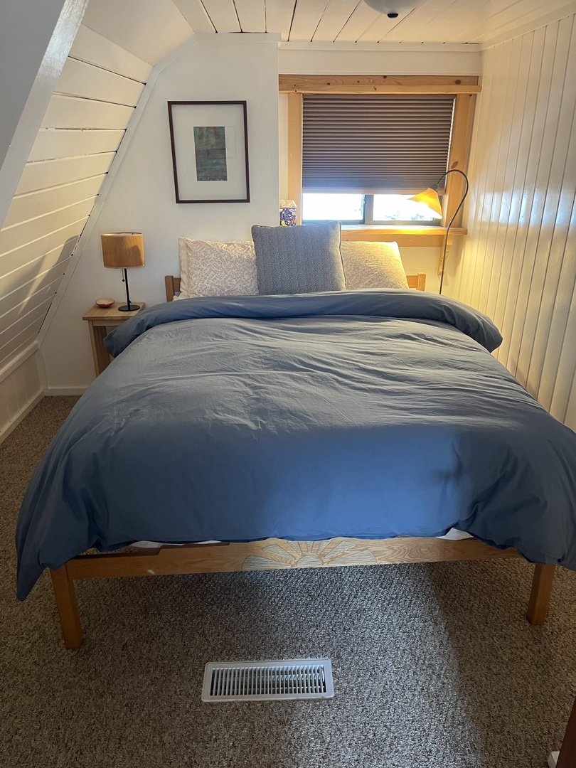 Curl up in this peaceful bedroom featuring crisp linens, soft lighting, and charming wood accents—your perfect retreat for restful nights.