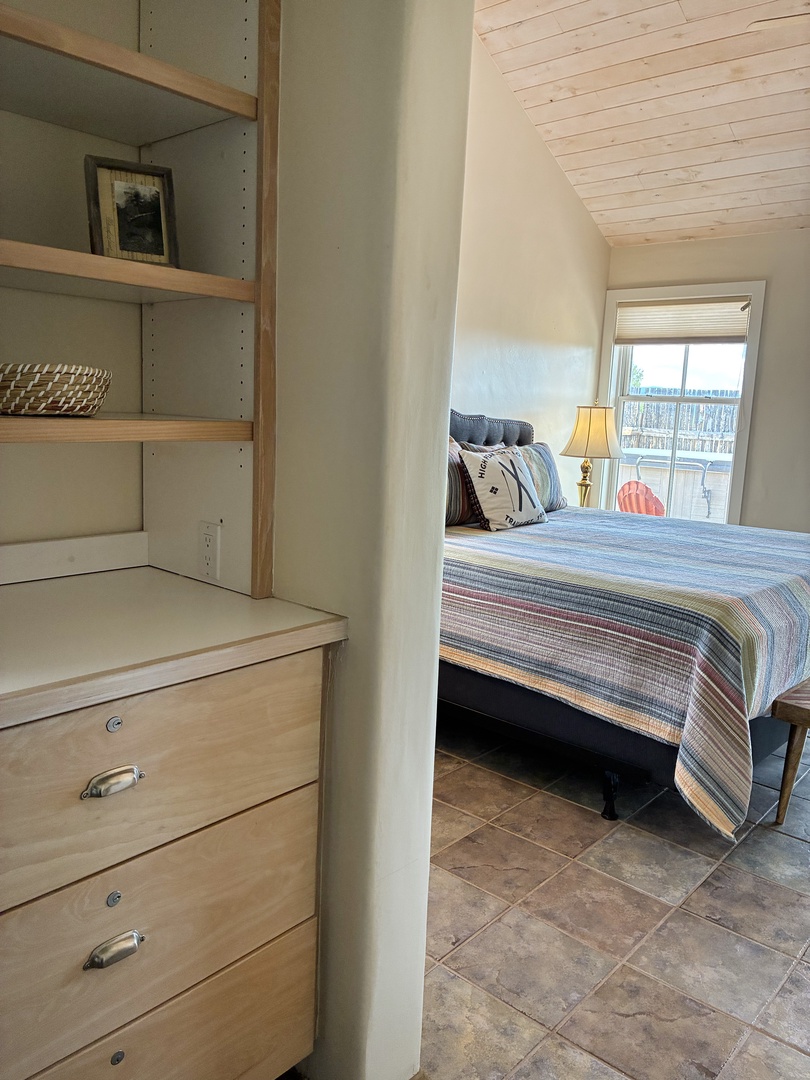 Unwind in your serene coastal bedroom with custom built-ins, tile flooring, and natural light streaming through the window.
