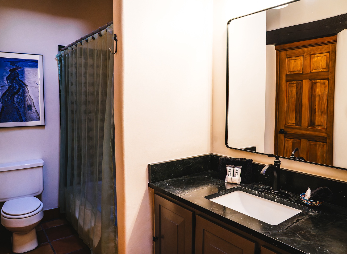 Refresh in your private bathroom featuring elegant marble countertops, warm wood cabinetry, and modern amenities for a comfortable stay.