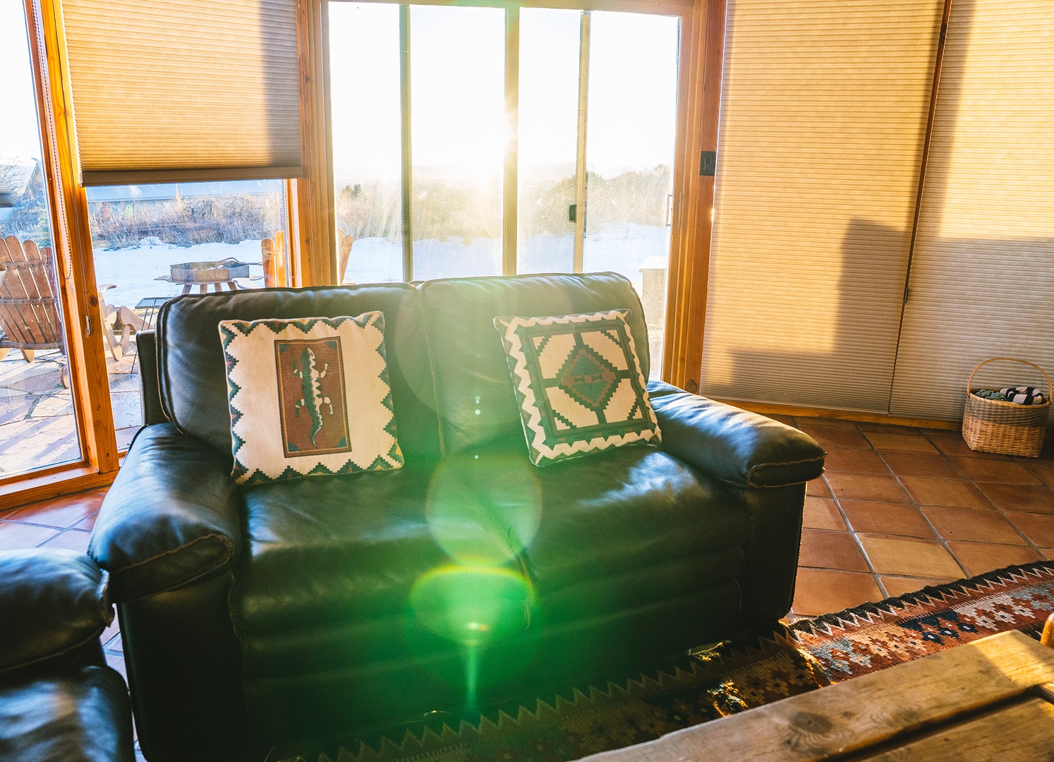 Sink into comfortable green leather seating while golden sunlight streams through large windows, creating a warm retreat with beautiful views.