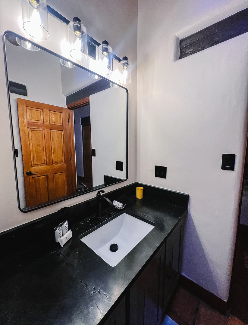 Your stylish bathroom features elegant dark countertops, modern lighting, and a sleek mirror for your daily routine.