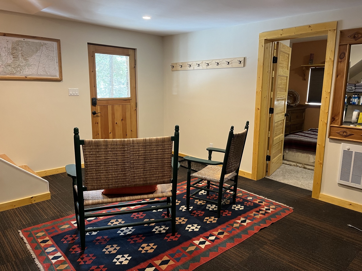 Cozy entryway with rustic wooden doors and woven seating on a vibrant geometric rug welcomes you into your retreat.