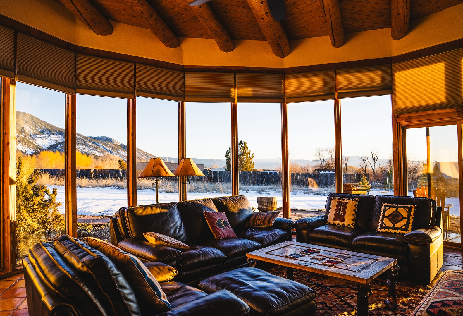 Sink into plush leather seating as winter sunlight streams through floor-to-ceiling windows, framing snow-dusted mountains and golden hour views.