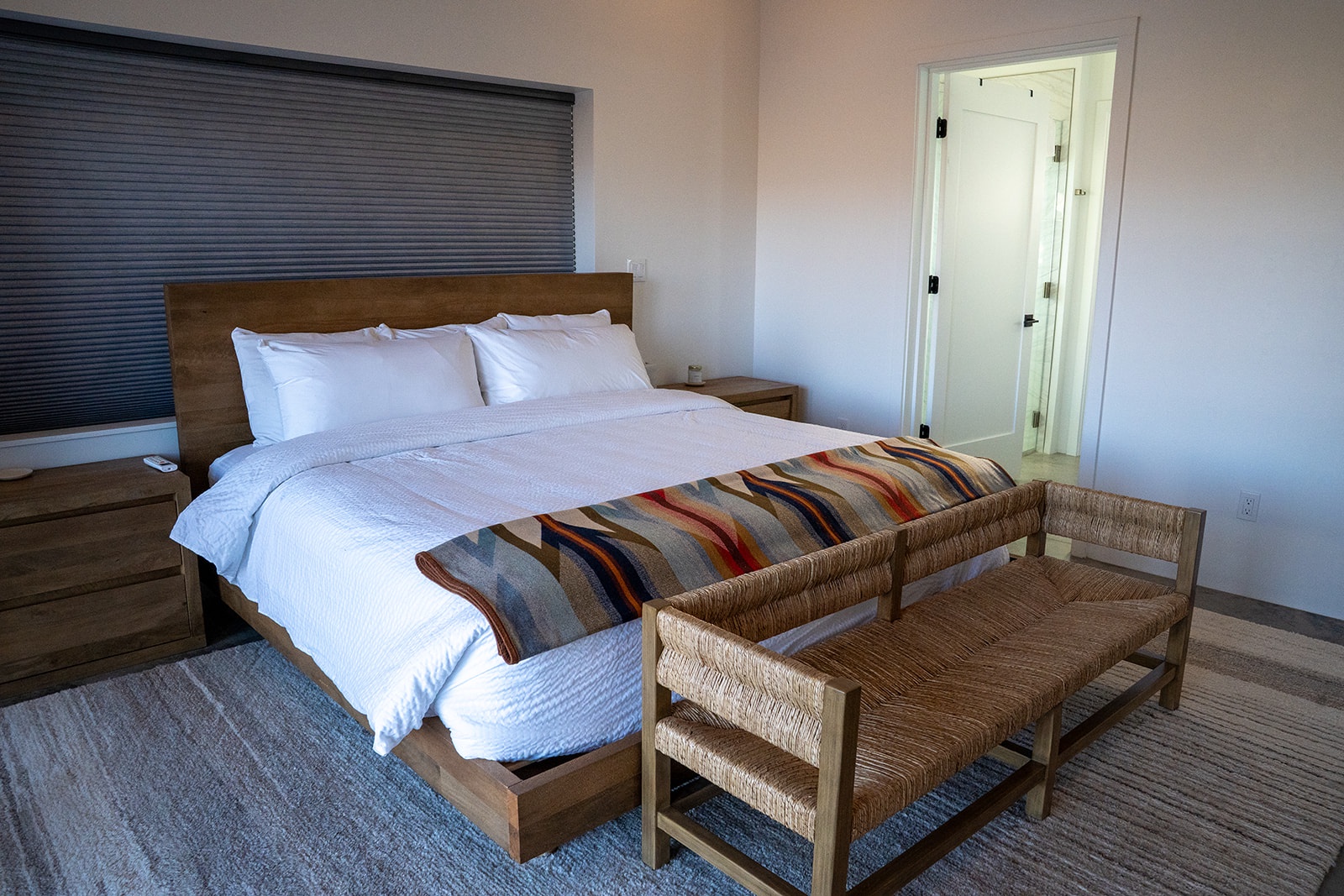 Sink into crisp white linens and wake refreshed in your thoughtfully designed bedroom with natural wood accents and cozy seating.