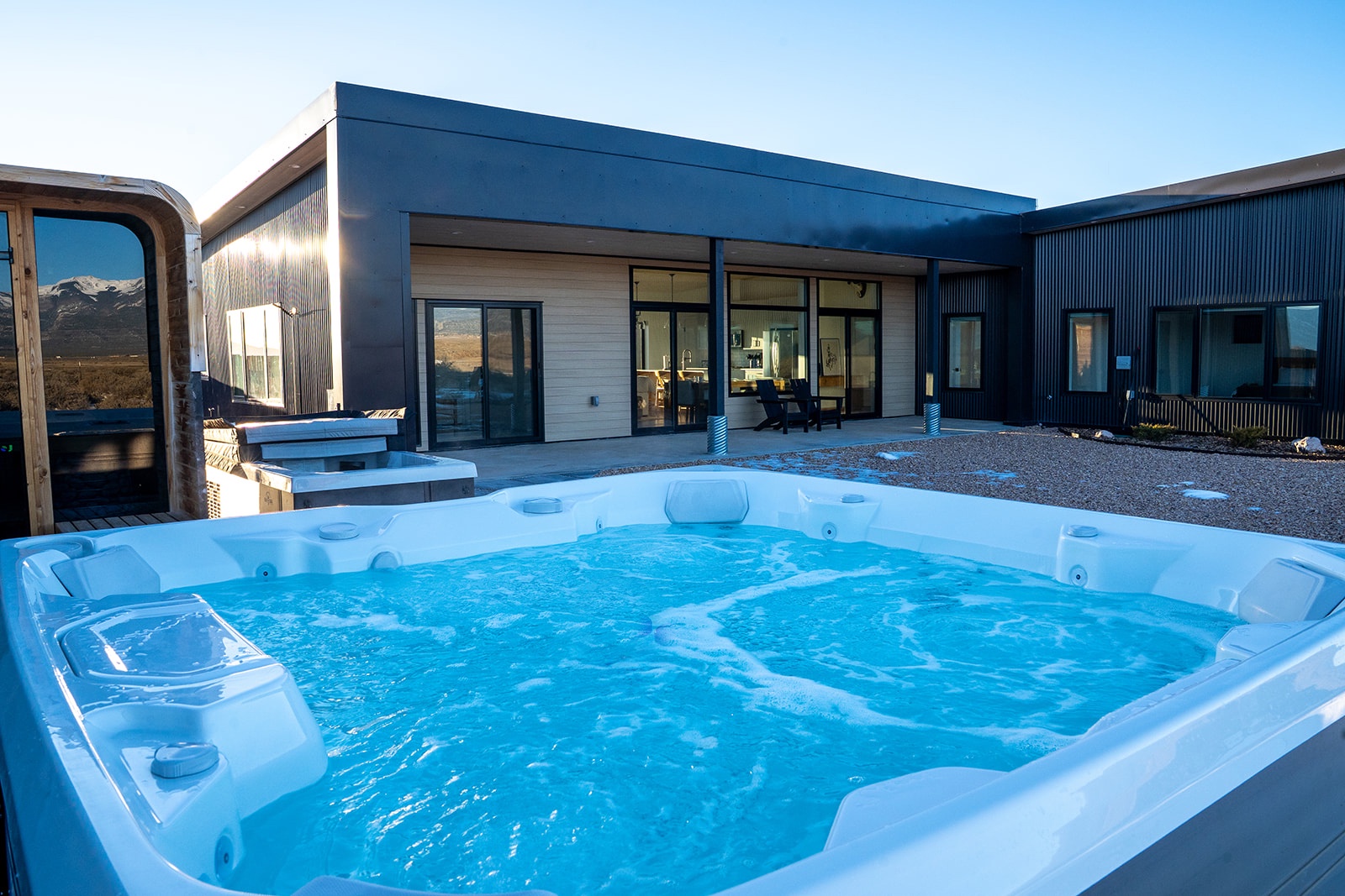 Soak in your private hot tub as the sun sets, with mountain views stretching beyond this modern retreat.