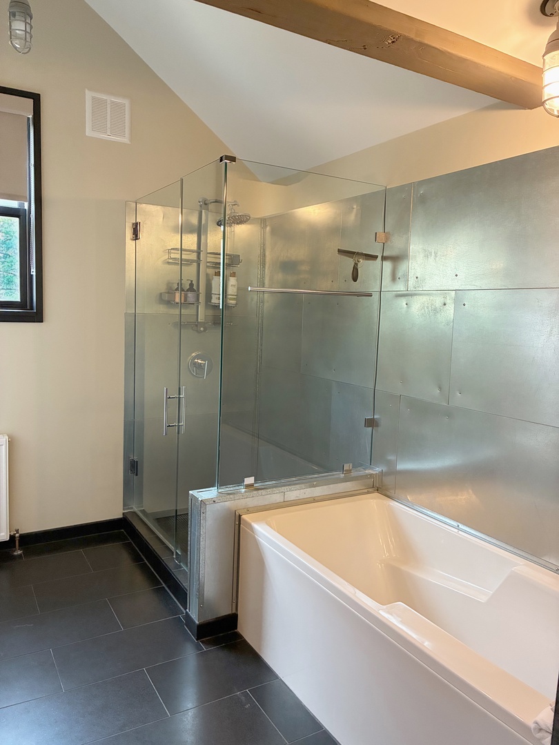 Soak in your private tub or refresh under the rainfall shower in this beautifully designed bathroom, where warm wood beams and spa-inspired finishes create a serene, luxurious retreat.