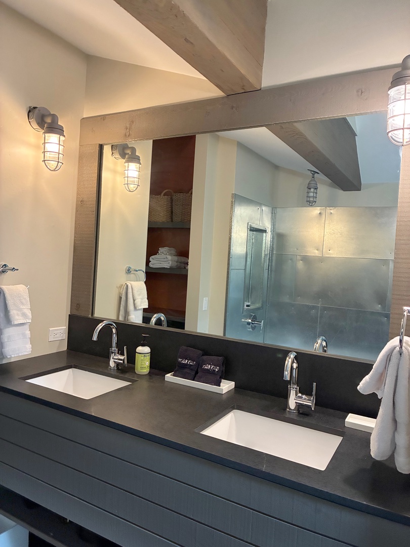 Refresh in your spa-inspired bathroom with dual vanities, modern fixtures, and exposed beam details that blend rustic charm with contemporary comfort.