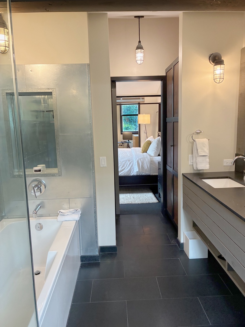 Step into your private spa-like sanctuary, where sleek lines and warm lighting set the mood for ultimate relaxation. A glass-enclosed bath and separate shower invite you to unwind in style.