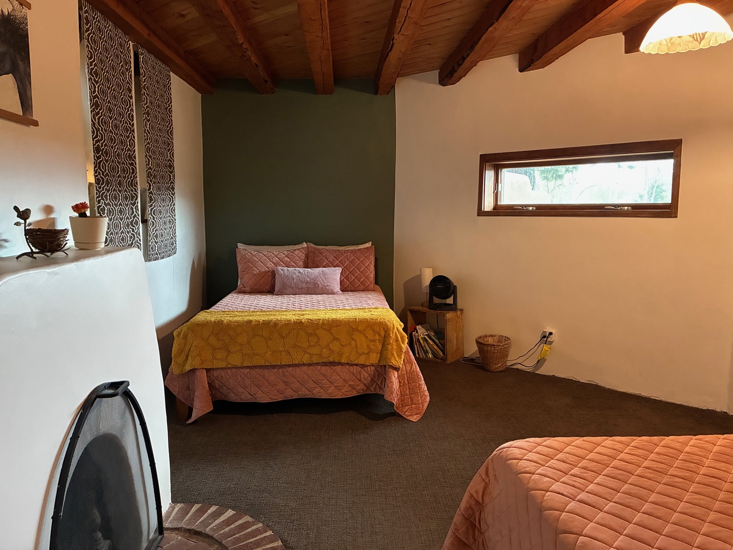 Unwind in your spacious bedroom with exposed wood beams overhead and a welcoming green accent wall that invites peaceful rest after a day of adventure.