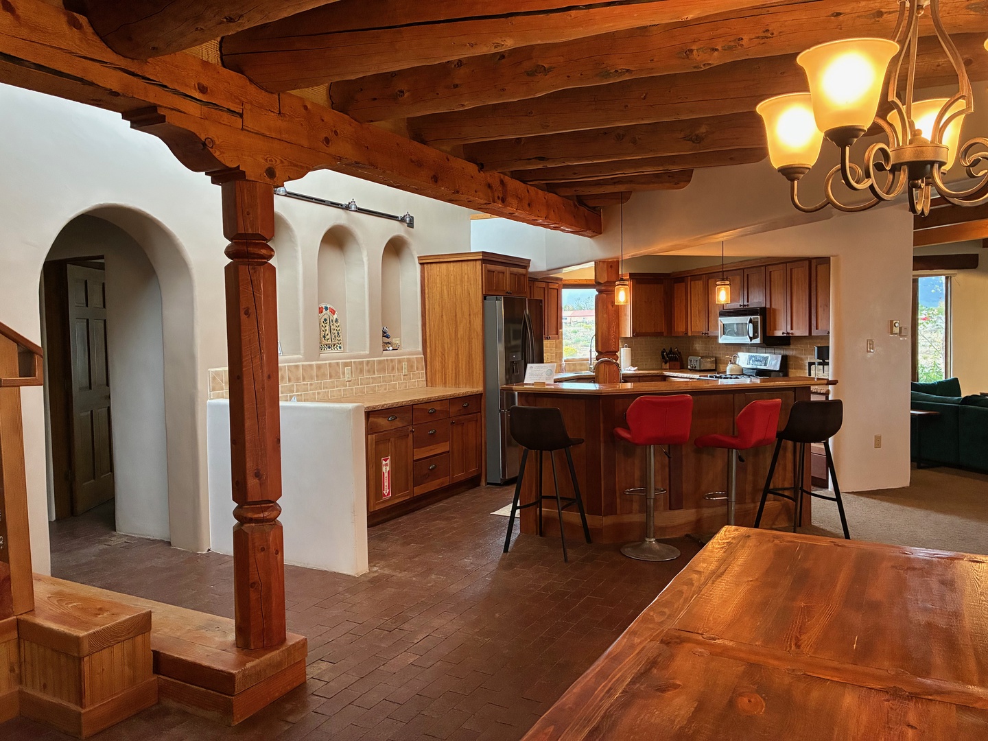 Step into your inviting kitchen and dining area, where rustic wood beams and warm lighting create a cozy mountain retreat atmosphere. Gather around the island with colorful bar seating, perfect for morning coffee or evening conversation.