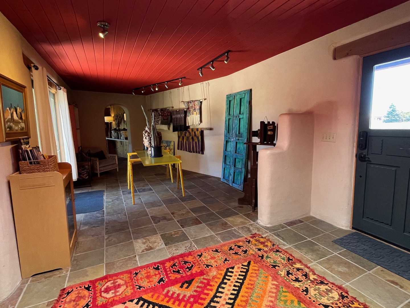 Step into this vibrant, art-filled space where a bold red ceiling and colorful decor create a warm, creative atmosphere.