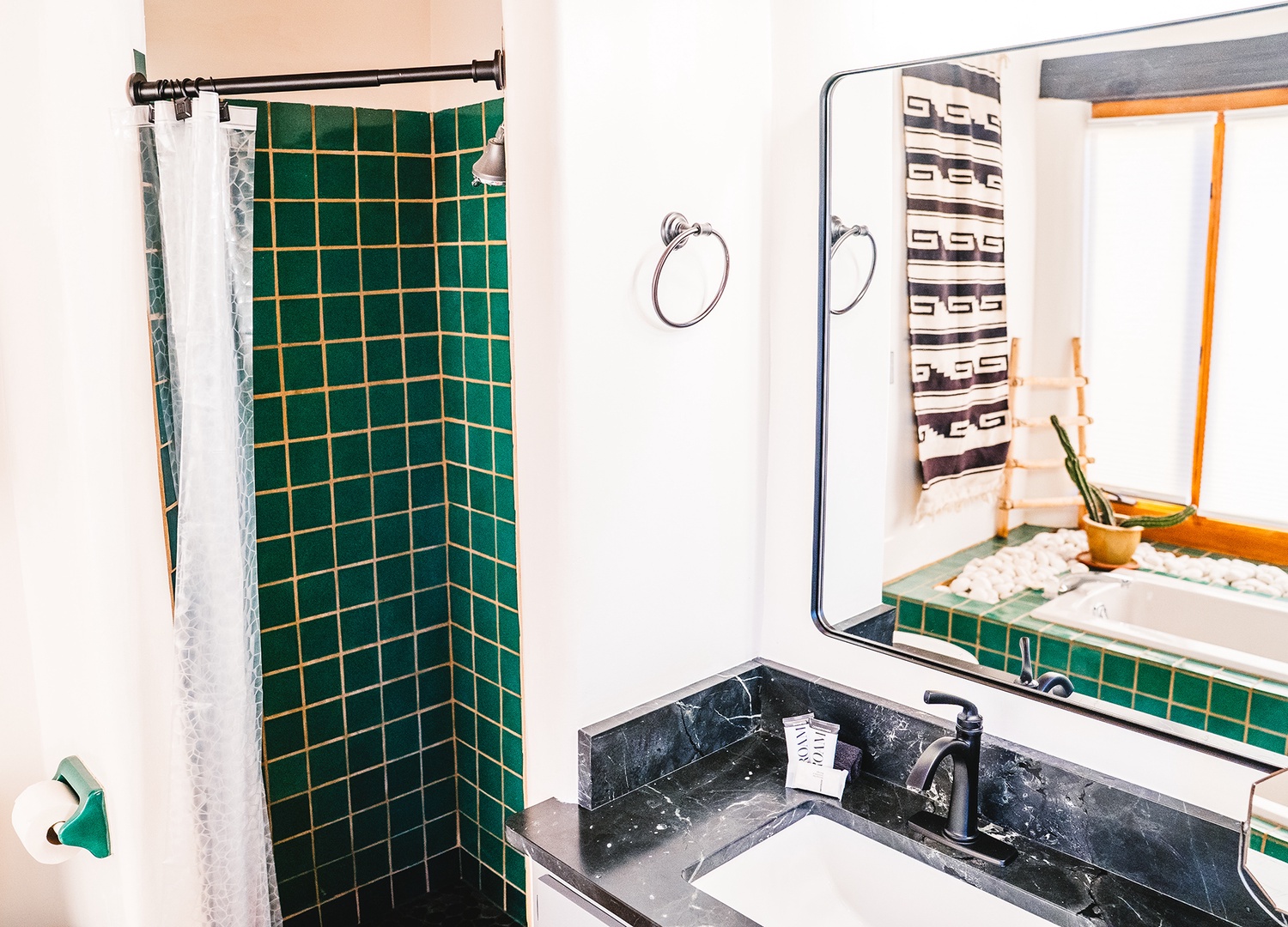 Your stylish bathroom features vibrant green tile work, a marble vanity, and all the essentials for a refreshing start to your day.