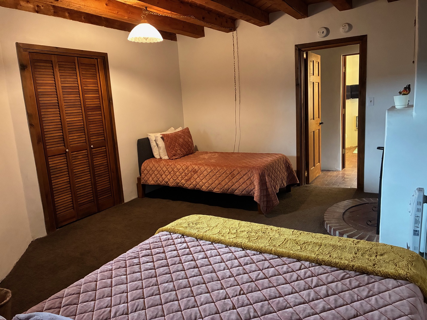 Unwind in your spacious bedroom with rustic wooden beams overhead and ample storage in the louvered closet. Two cozy beds await, ready to welcome you after a day of adventure.