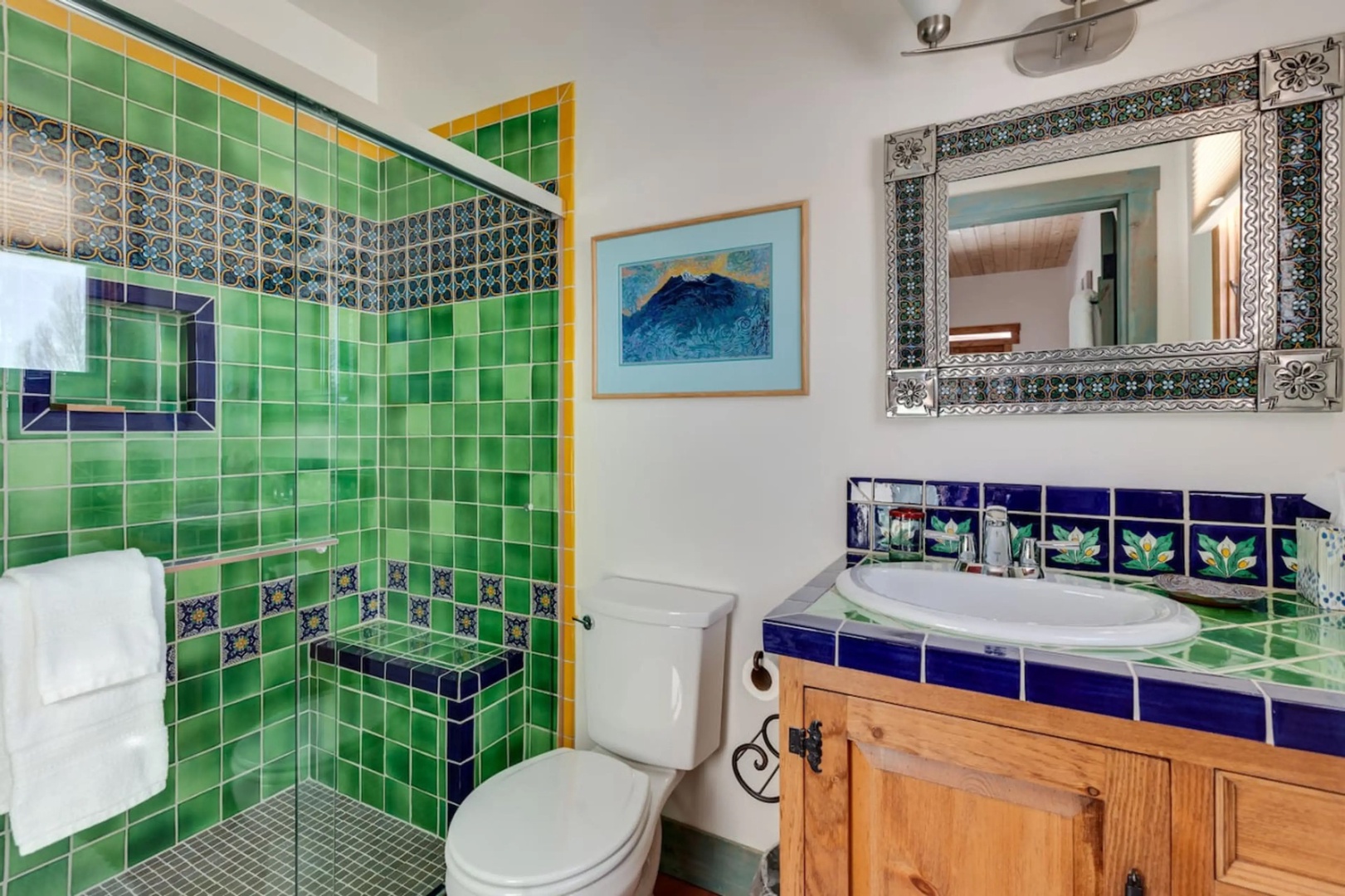 Step into your private bathroom where vibrant Mexican tiles in emerald and cobalt create an artful retreat. The spacious walk-in shower and hand-painted details add authentic charm to your daily routine.