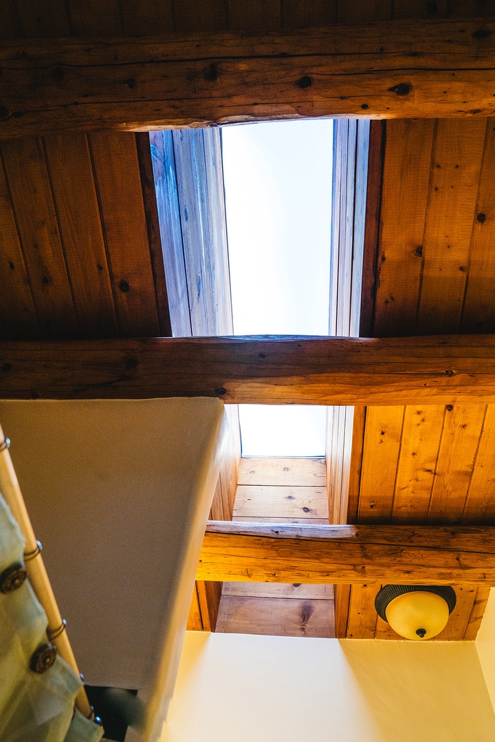 Look up to discover charming skylights that fill your rustic retreat with natural light through beautiful exposed wood beams.