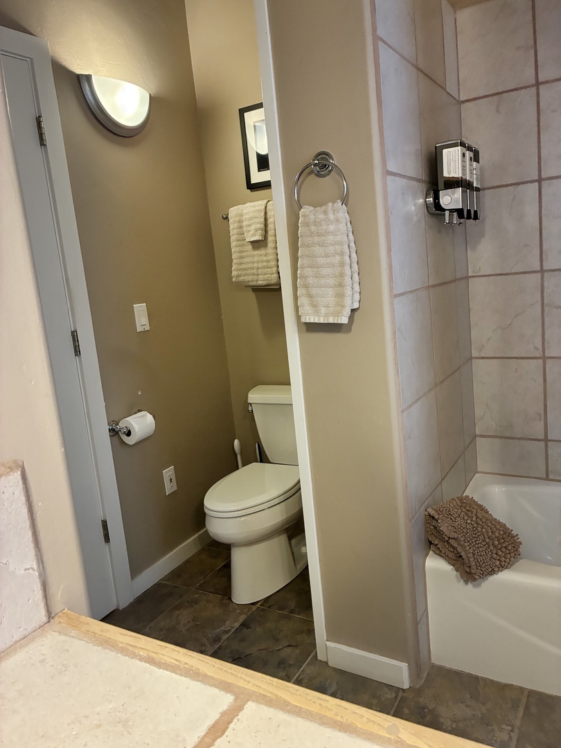 Your private bathroom features soft lighting, plush towels, and a spacious walk-in shower with a convenient dispenser. Everything you need is thoughtfully arranged for a refreshing start to your day.