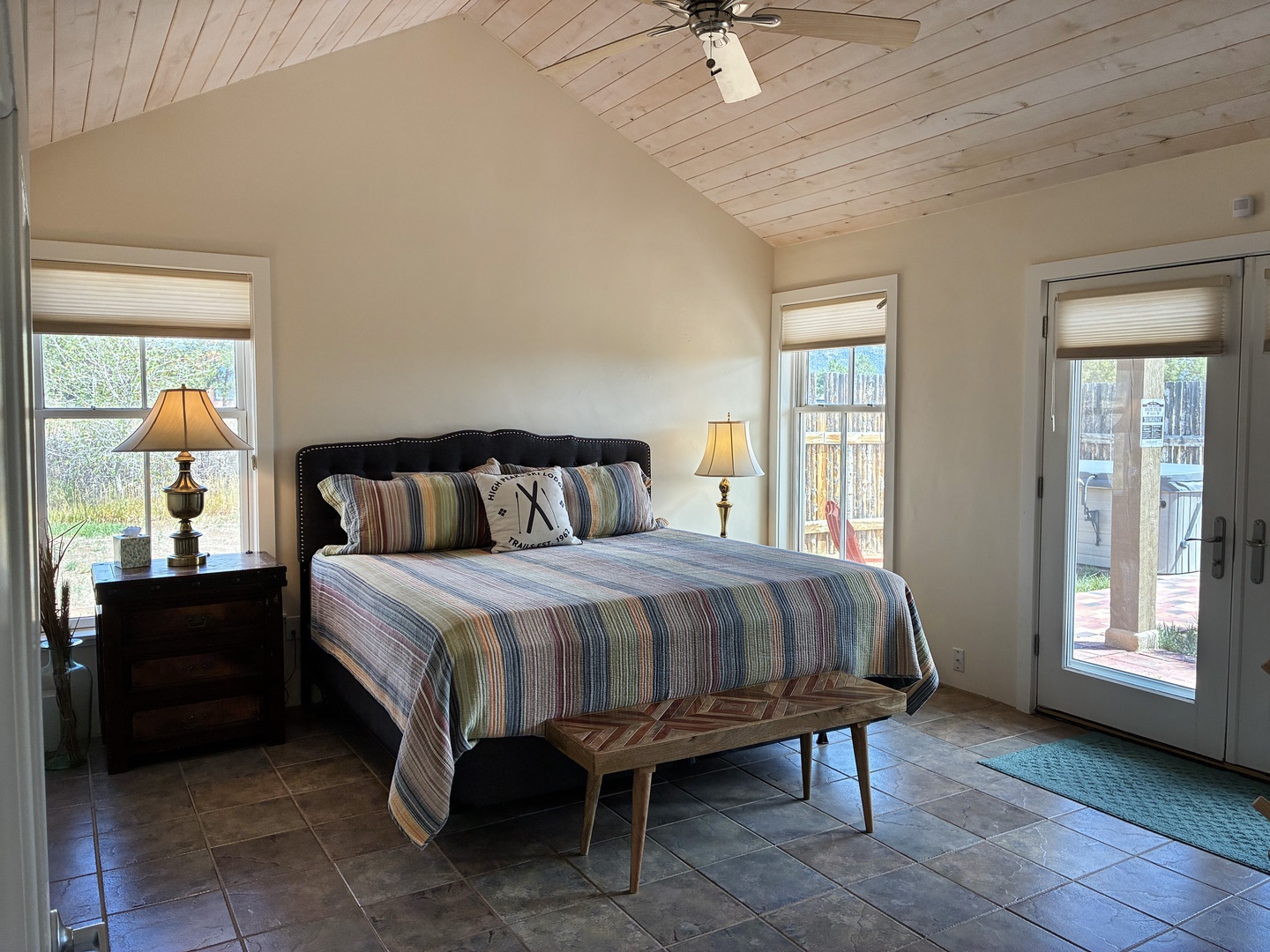 Step into your peaceful retreat with vaulted wood ceilings and French doors opening to your private outdoor space. The coastal-inspired bedding invites restful nights while natural light pours through generous windows.