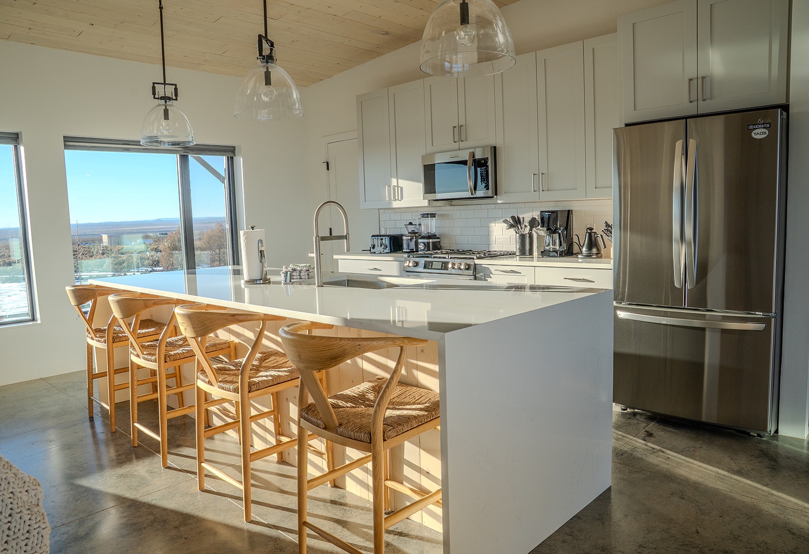 Your modern kitchen features pristine white cabinetry, stainless steel appliances, and a stunning breakfast bar where you'll enjoy morning coffee with panoramic water views.