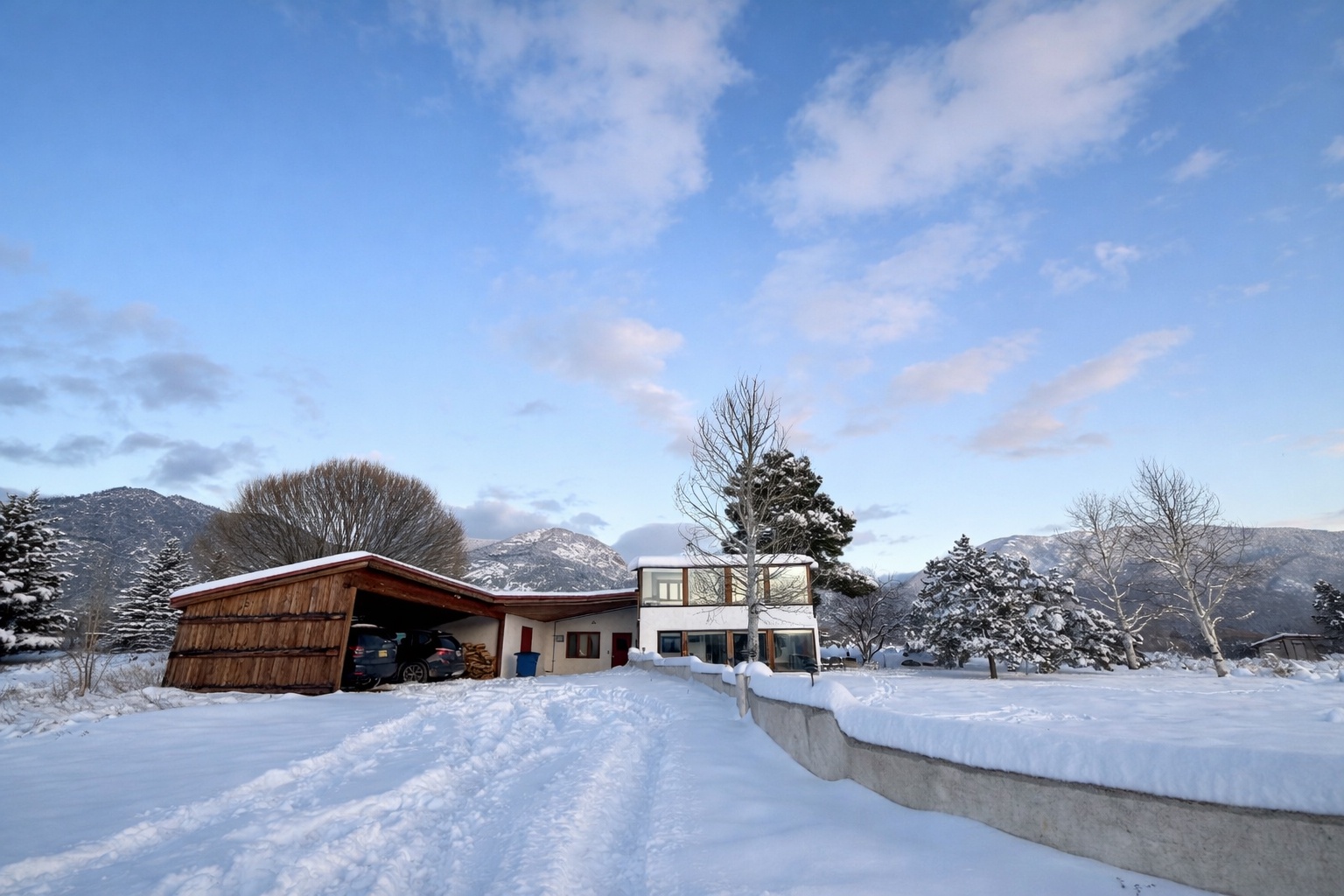 Modern mountain retreat nestled in pristine winter landscape with snow-capped peaks and peaceful alpine setting.