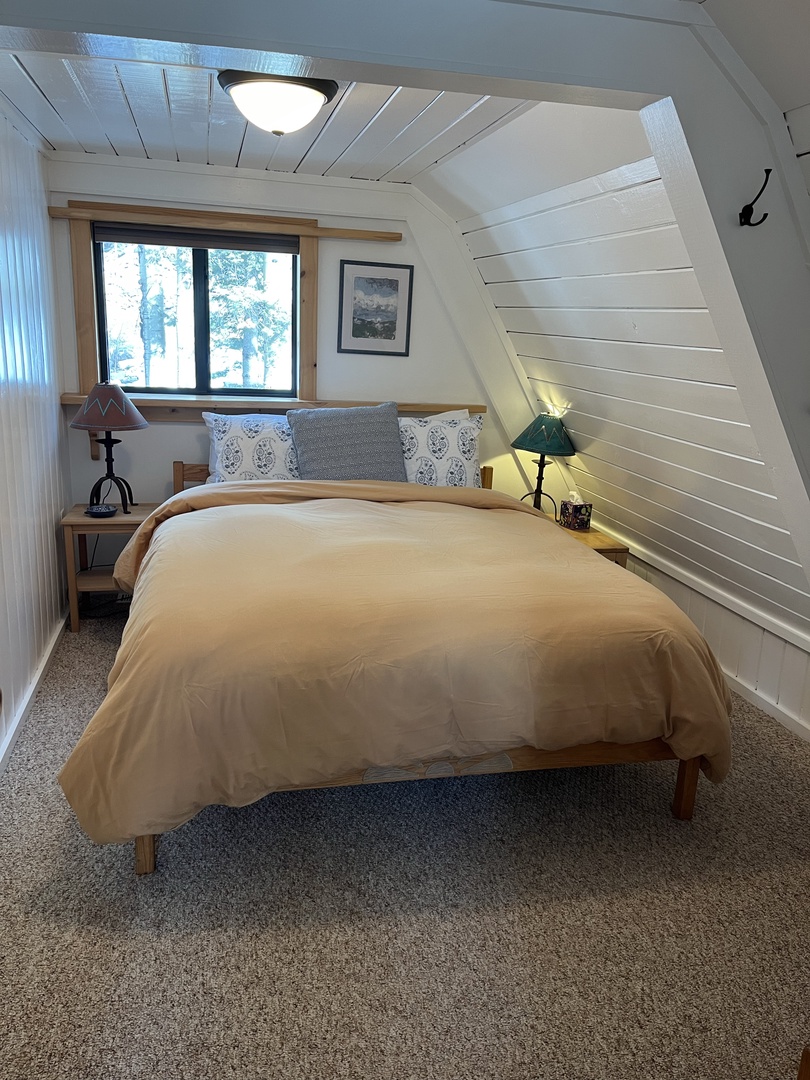Drift off beneath whitewashed shiplap ceilings in your cozy loft bedroom. Soft linens, woodland views, and gentle natural light create the perfect mountain retreat.