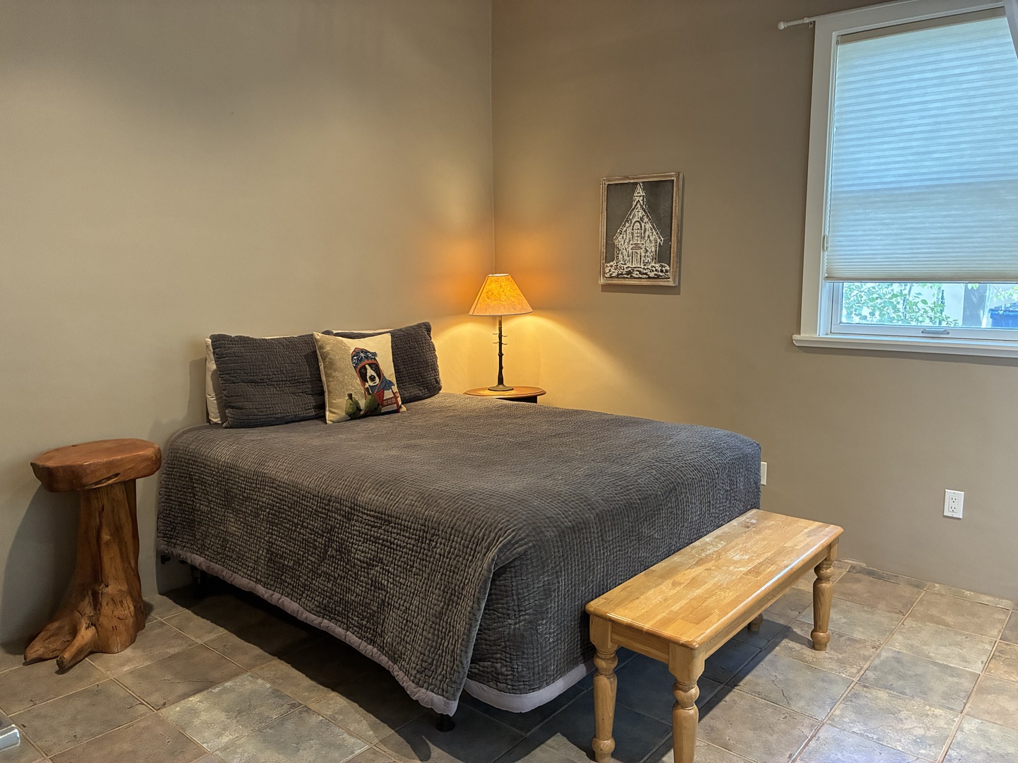 Settle into your restful bedroom corner, where a plush bed and warm bedside lamp welcome you after a day of exploring. Natural light streams through your window, while thoughtful rustic touches make the space feel like home.