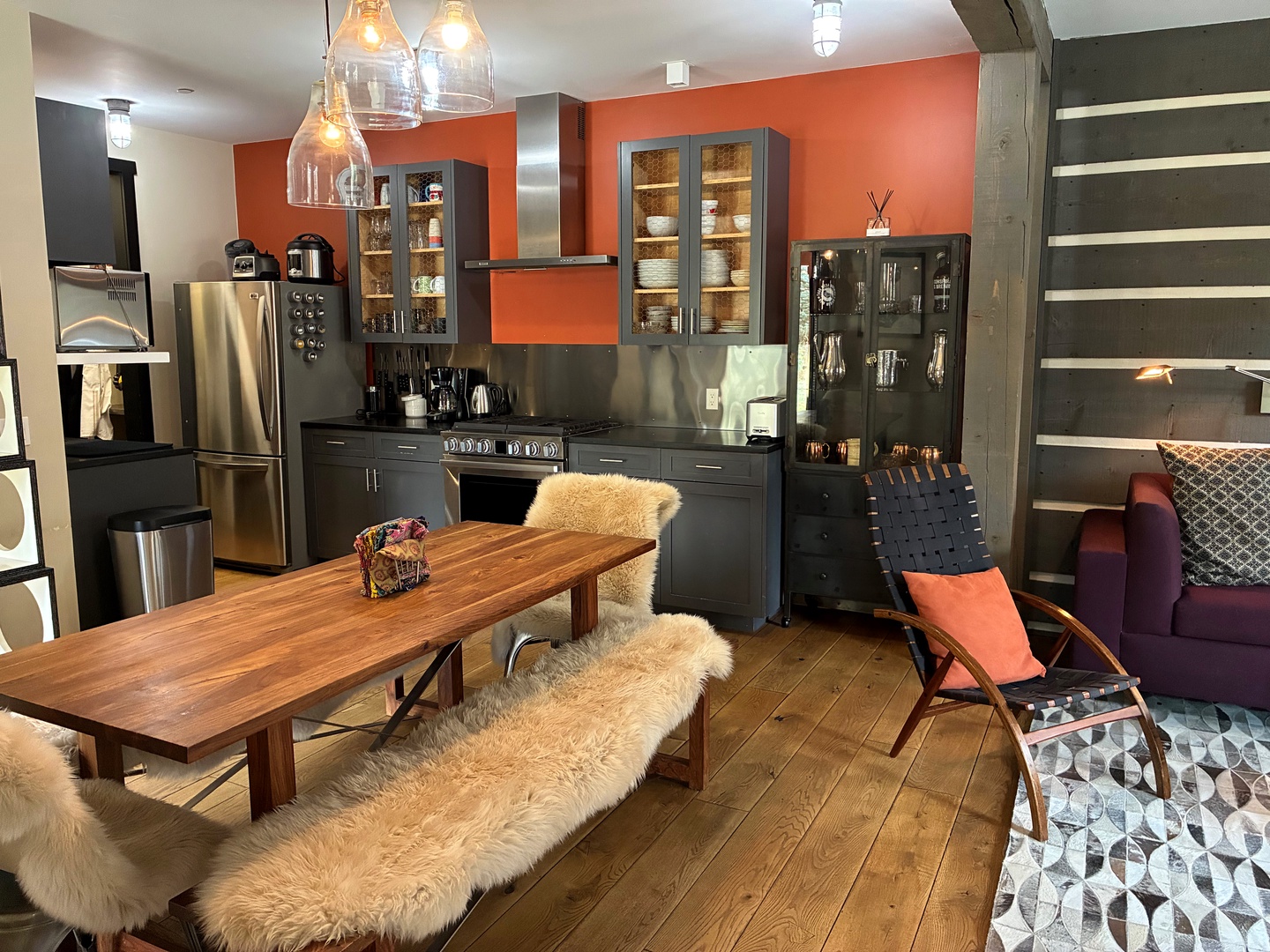 Step into this stylish open-plan living space where your culinary adventures await. The modern kitchen gleams with stainless steel appliances and warm wooden dining table, while plush seating invites you to relax after a day exploring.