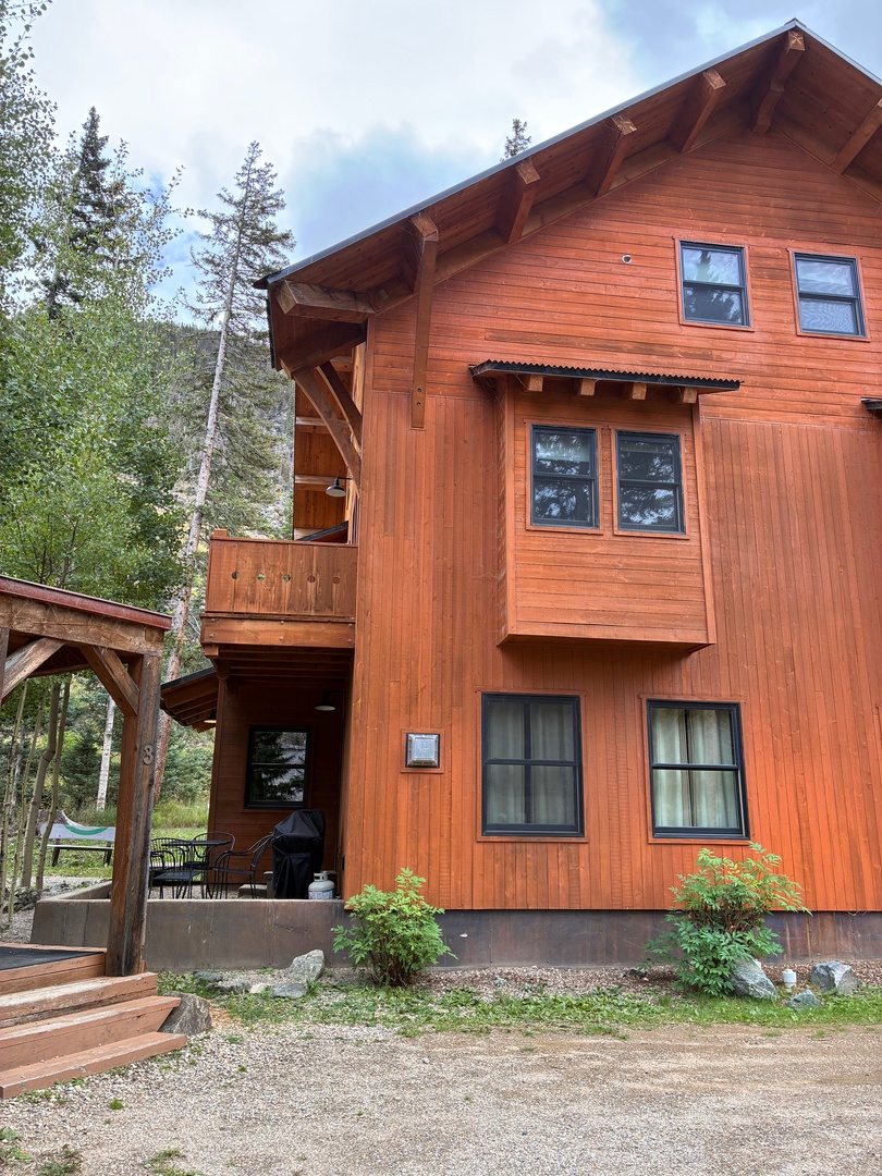 A striking wooden chalet surrounded by towering evergreens and mountain scenery, featuring multiple levels and spacious balconies—your peaceful retreat awaits.