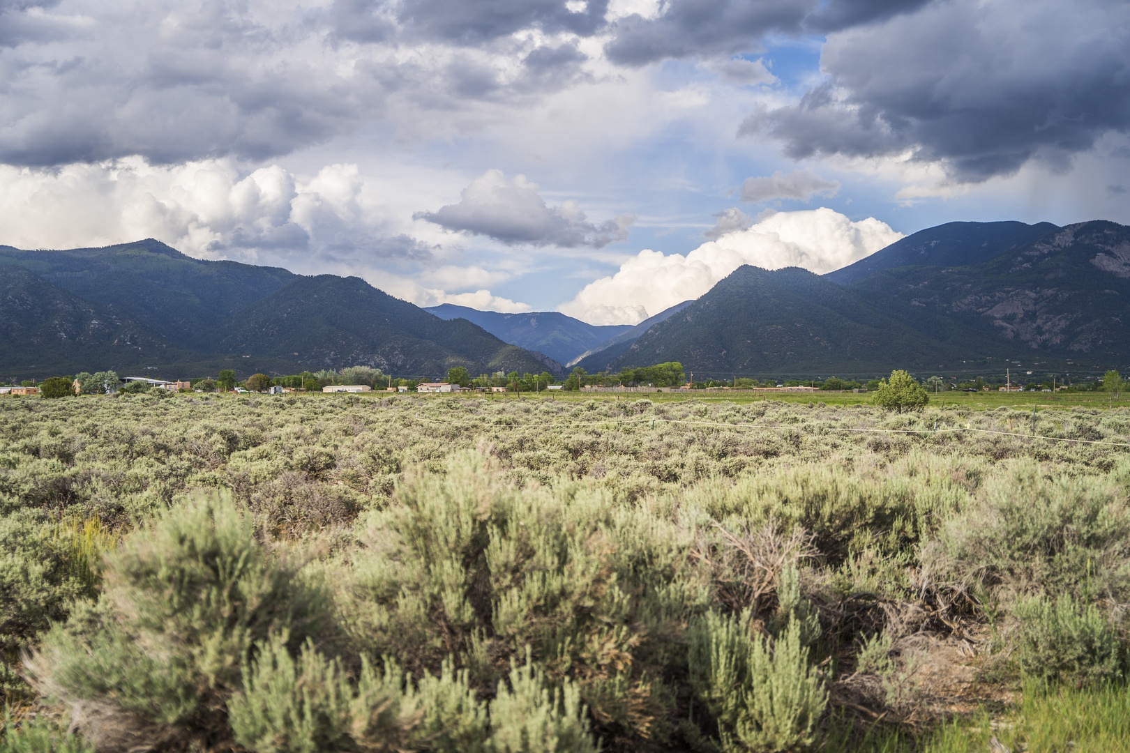 A sweeping view of sagebrush desert backed by mountain ridges beneath dramatic clouded skies, capturing the natural landscape surrounding the property.