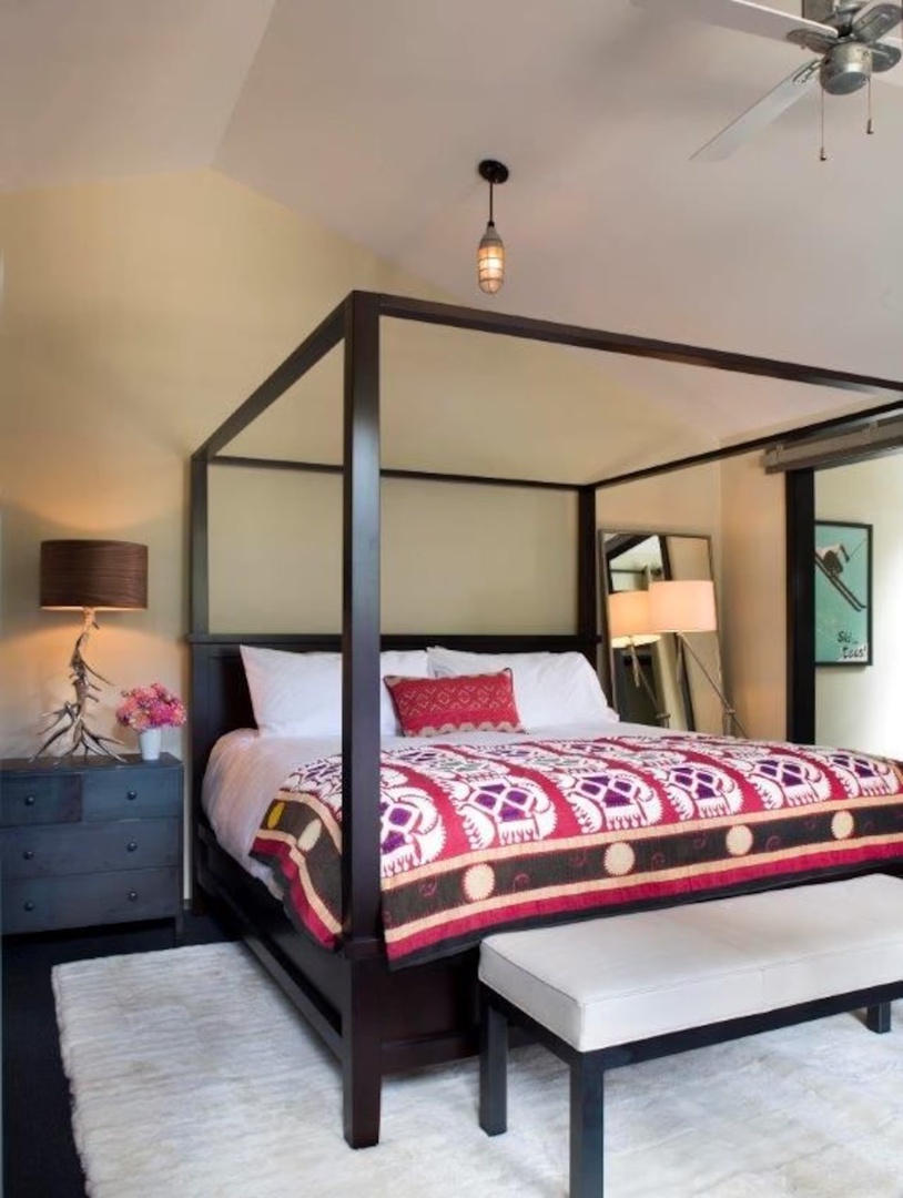 Sink into plush bedding beneath your own canopy frame, where vibrant textiles and soft lighting create a restful retreat. This stylish bedroom invites you to unwind in comfort and charm.