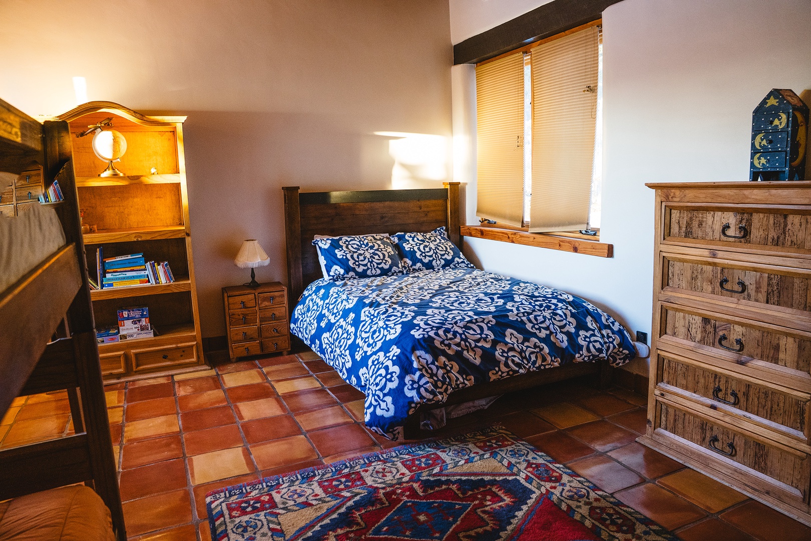 Relax in this charming bedroom with rustic wood furniture, colorful textiles, and warm lighting creating your perfect retreat.