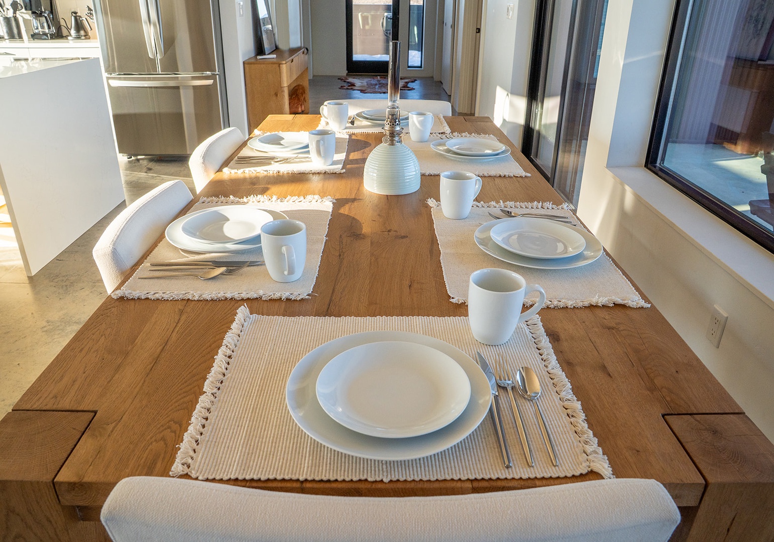 Your modern dining space awaits with natural wood warmth and bright sunshine streaming through floor-to-ceiling windows.