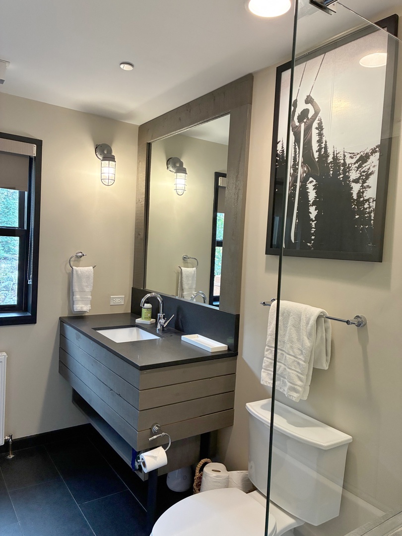 Step into your sleek, modern bathroom with fresh towels waiting for you. The walk-in shower and floating vanity create a spa-like feel, while natural light from the window adds warmth to your daily routine.