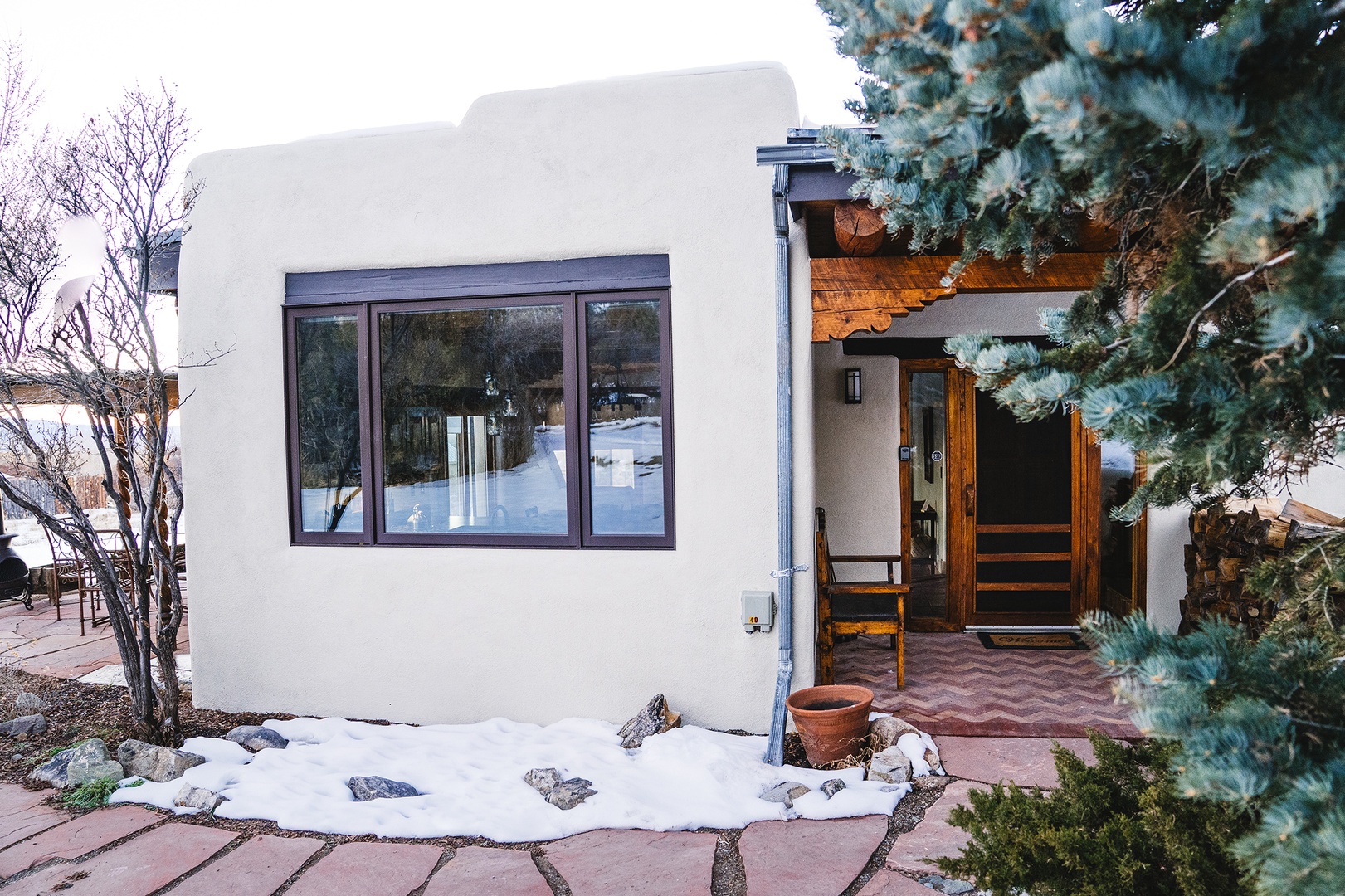 Modern adobe-style retreat with warm wood accents nestled among evergreens, offering a peaceful winter getaway with contemporary comfort.
