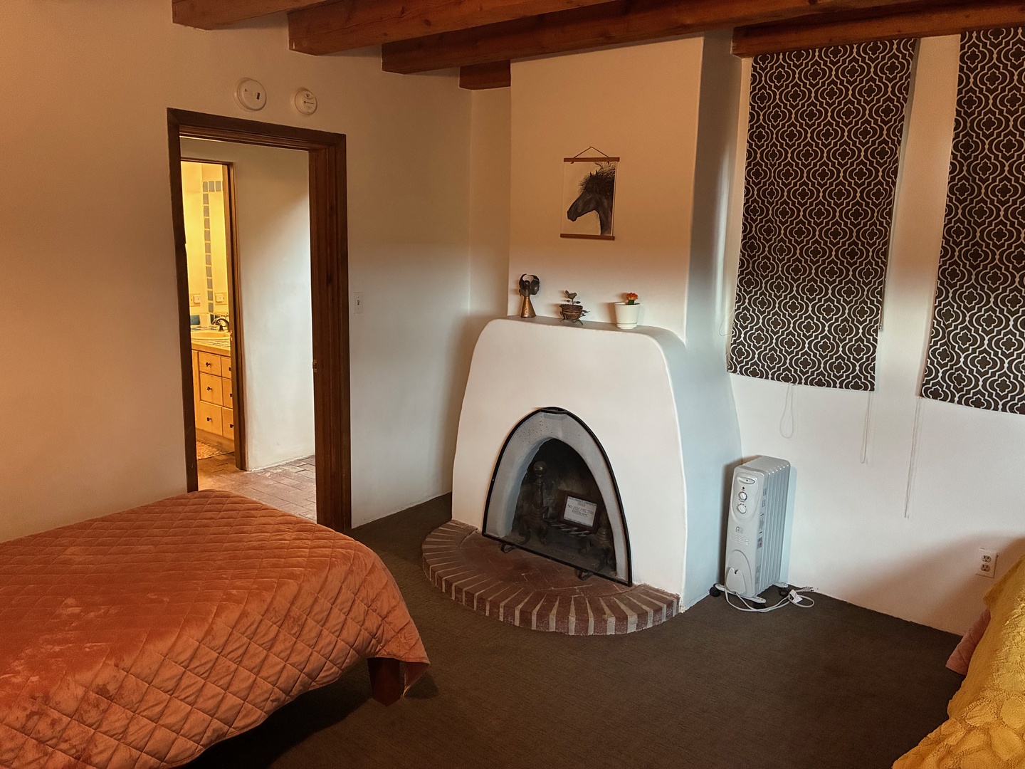Your cozy bedroom features authentic exposed wood beam ceilings and a charming adobe-style fireplace that adds warmth and Southwestern character to your restful retreat.