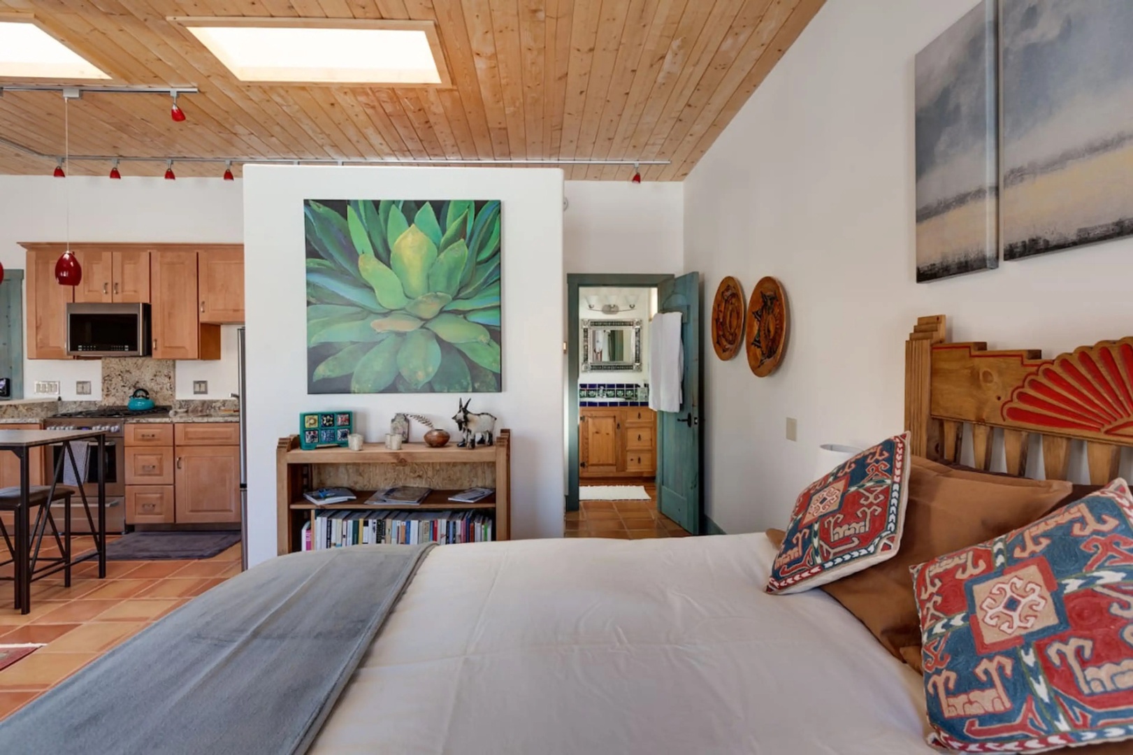Relax in your bright, open bedroom with soaring wood ceilings and a skylight that fills the space with natural light. The cozy bed and Southwest-inspired decor welcome you into a warm, artistic retreat.