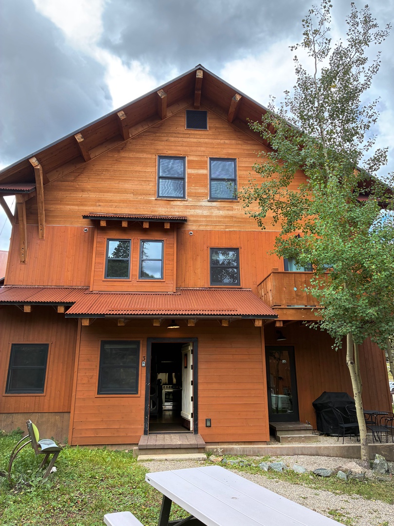 A spacious three-story mountain lodge with warm wood siding and a striking A-frame design welcomes guests to a serene outdoor escape.