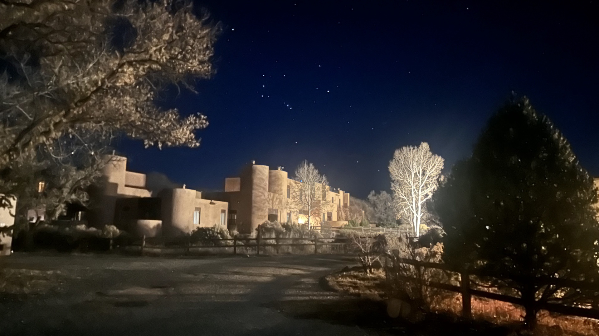 A stunning night view showcases the property's adobe-style architecture beneath a starlit sky, creating a magical southwestern atmosphere.