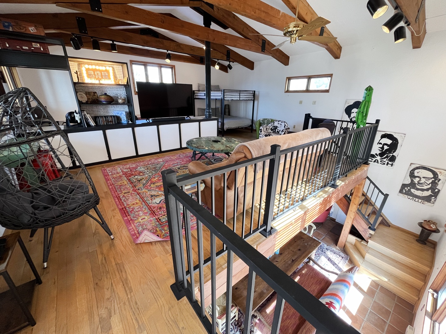 Cozy loft with exposed beams and bunk beds overlooks the inviting living area below through stylish railings.