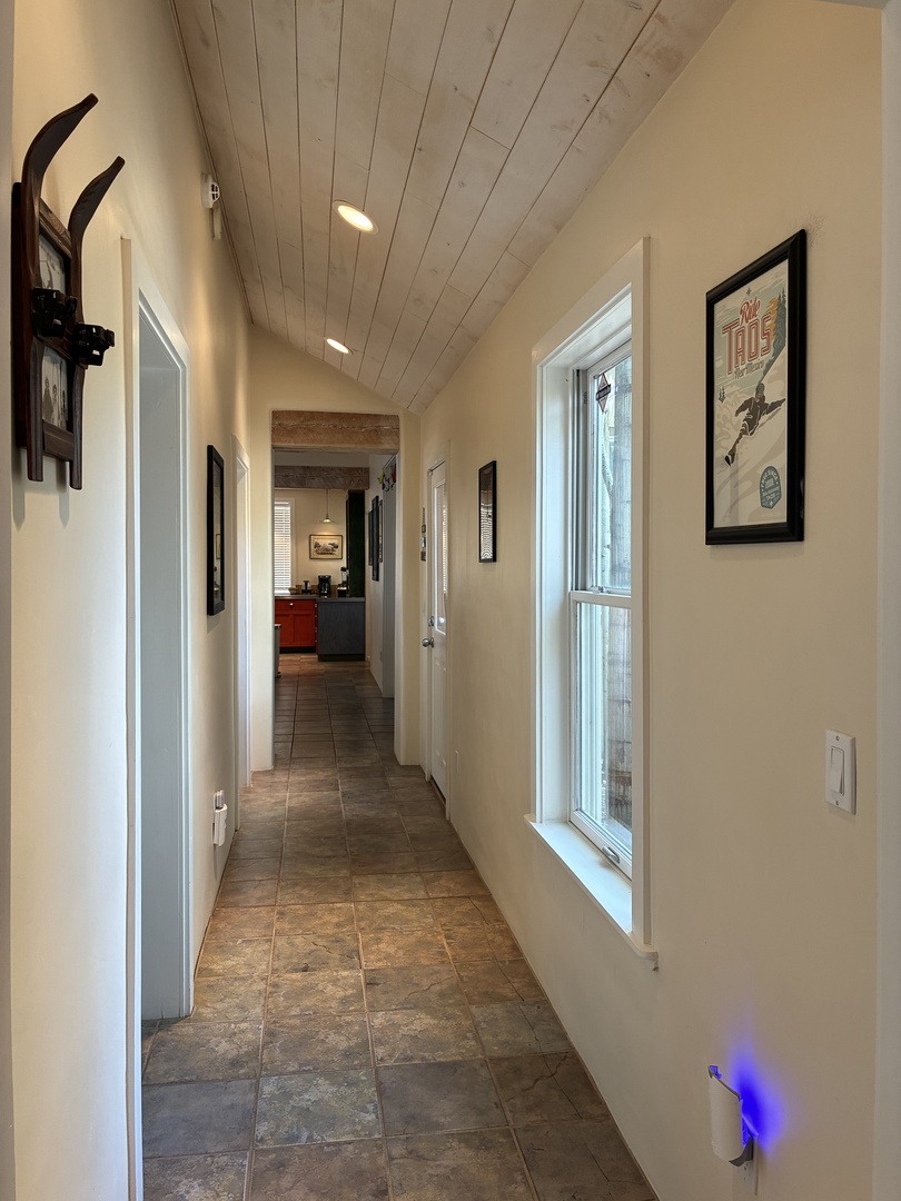 Rustic wood-planked ceilings guide you through this inviting hallway, where soft lighting and vintage ski decor create a warm alpine atmosphere as you settle in.