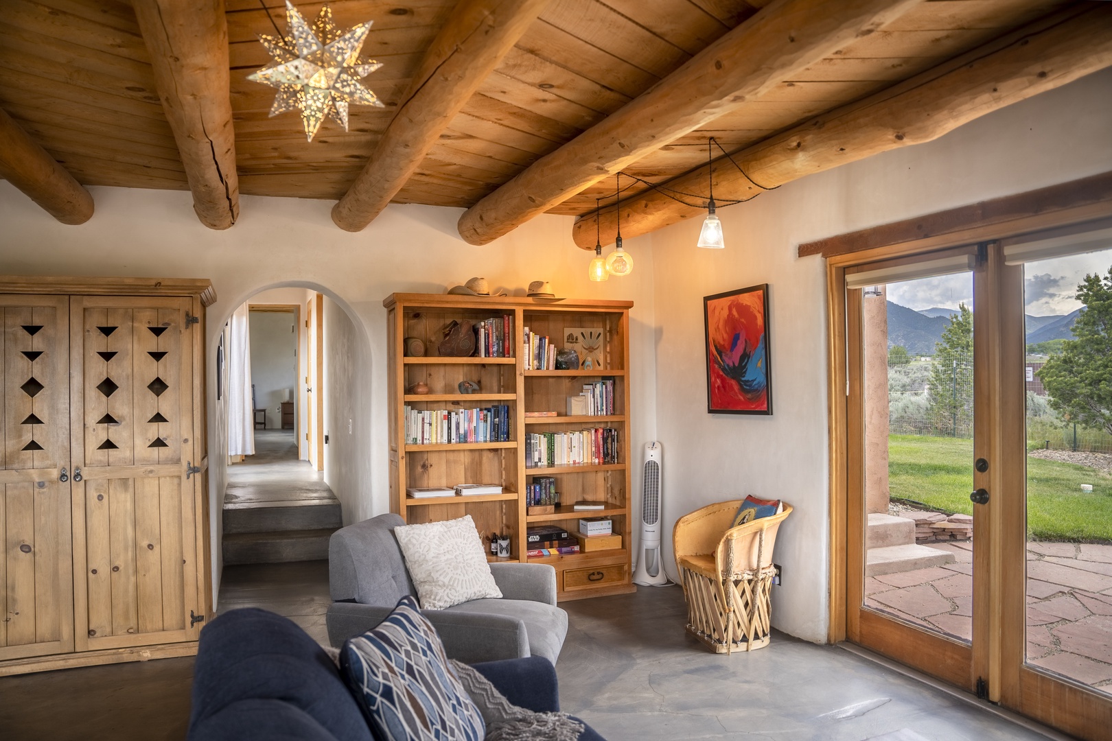 Settle into your cozy reading nook under rustic timber beams, where peaceful mountain vistas greet you through the glass door and warm natural light fills your retreat.