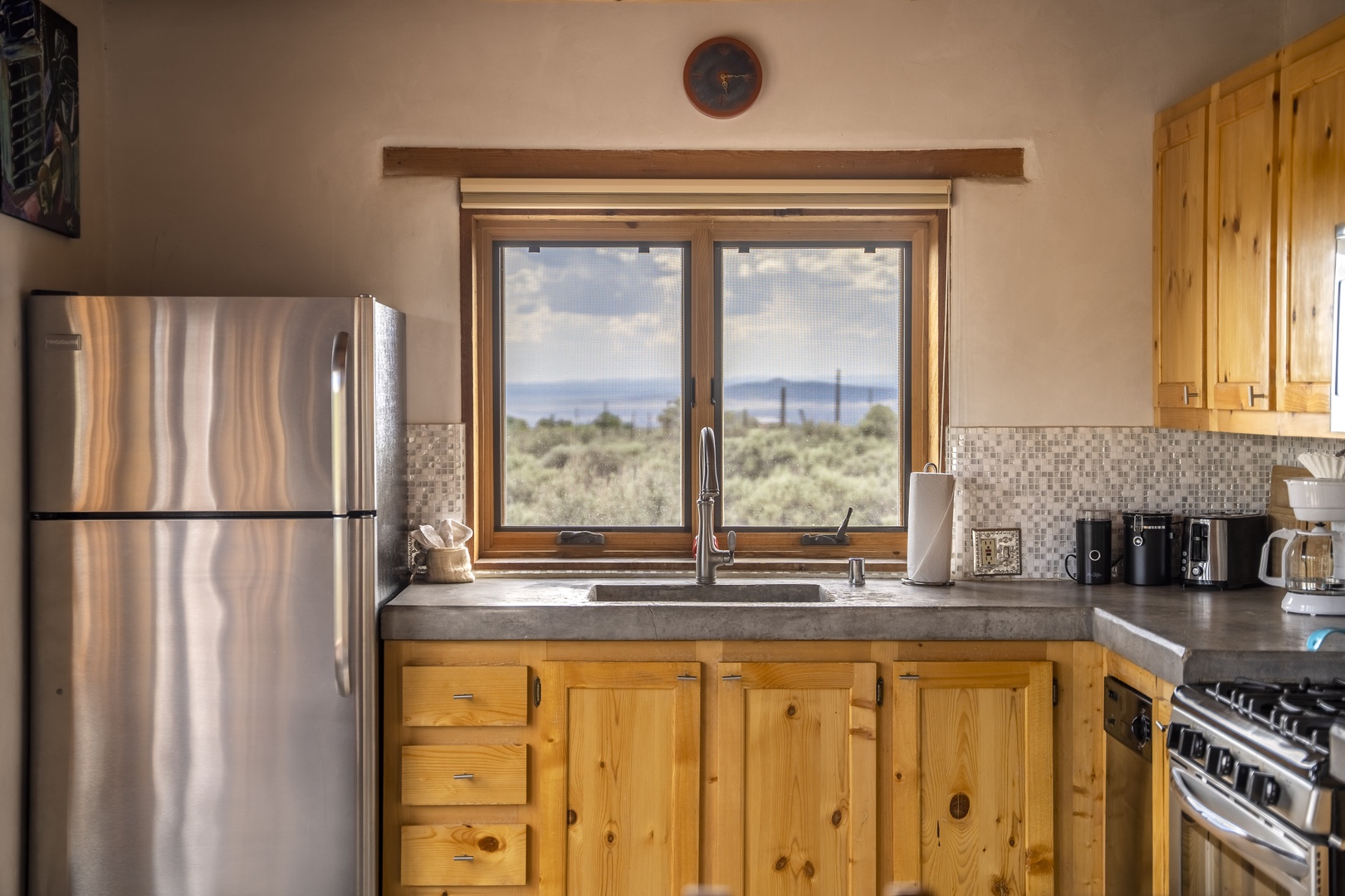 Prepare your favorite meals with stunning high-desert views as your backdrop. The fully equipped kitchen features stainless steel appliances, rustic pine cabinetry, and panoramic windows overlooking native sagebrush and distant mountains.