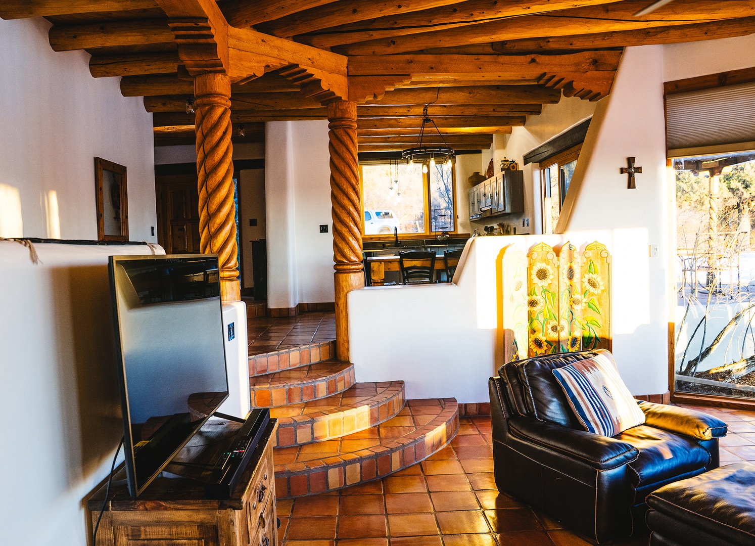 Relax in your charming Southwest-style living room, where rustic wooden beams frame cozy leather seating and warm terracotta tiles beneath your feet.